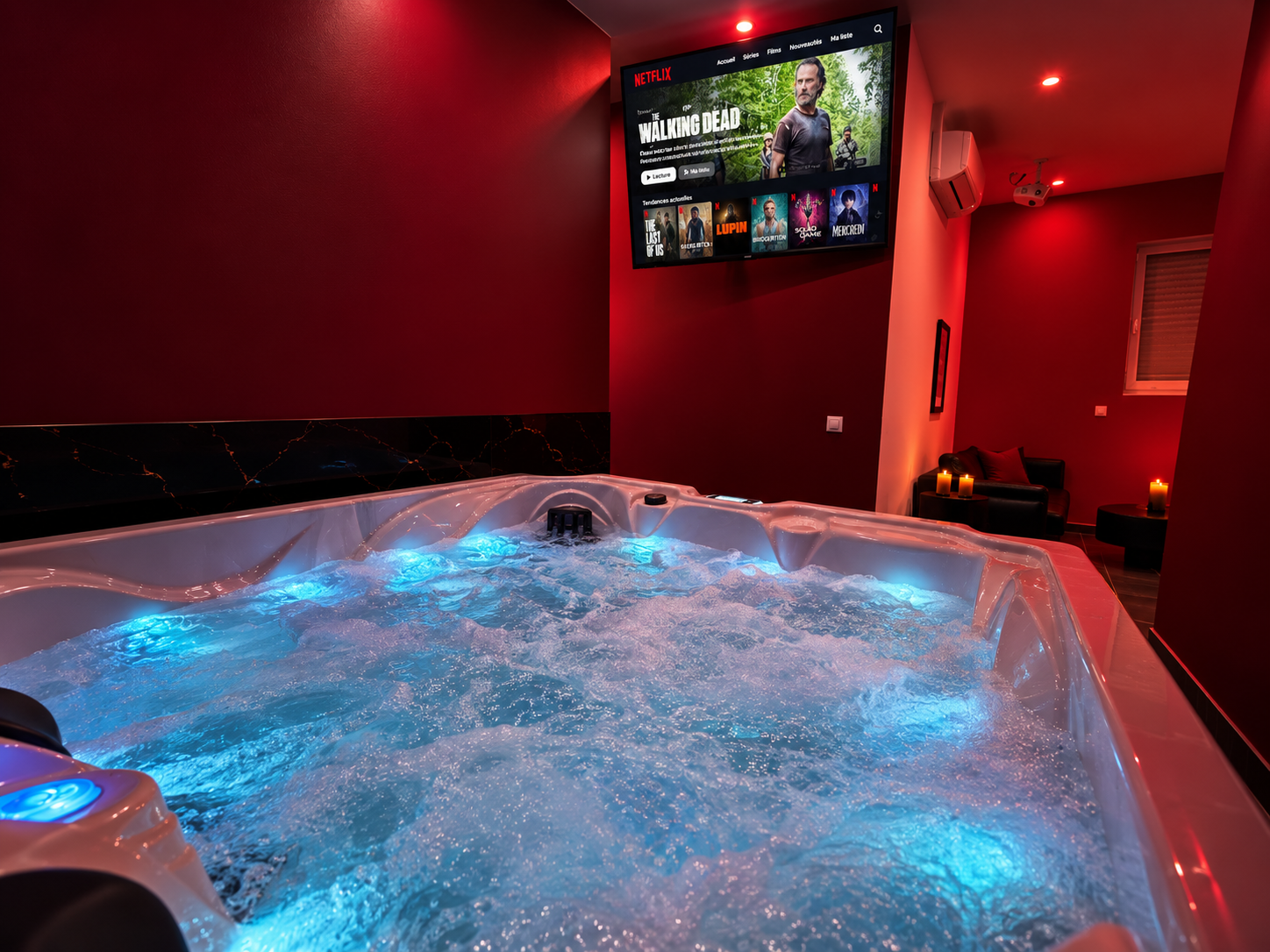 Jacuzzi privatif avec éclairage bleu et télévision, dans une ambiance rouge et noire.