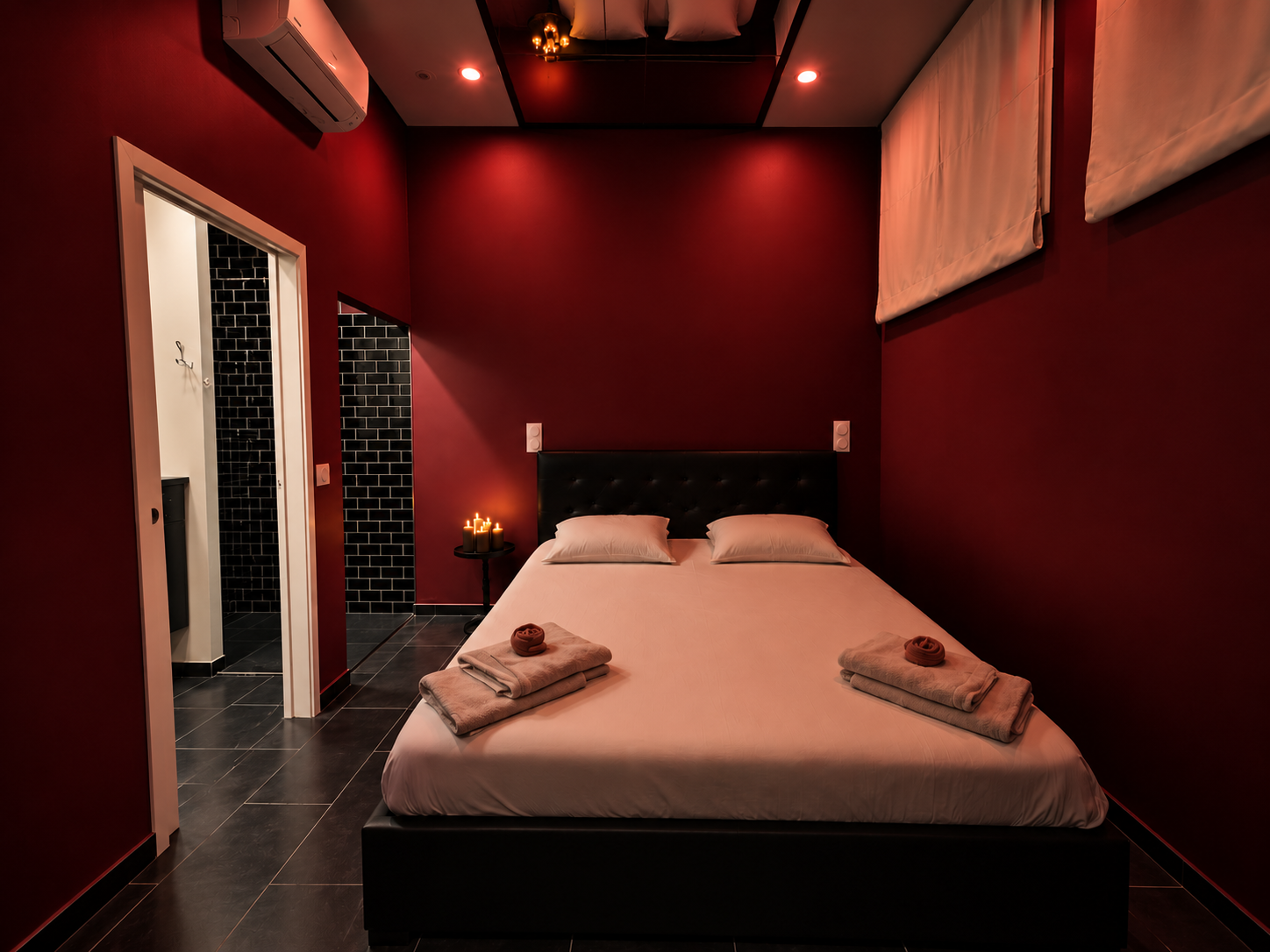 Chambre rouge et noire avec lit double et miroir au plafond.