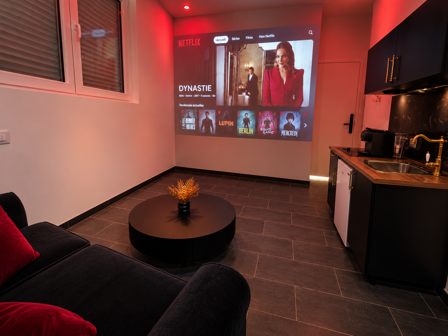 Salon avec canapé et projection cinéma, à côté de la cuisine.